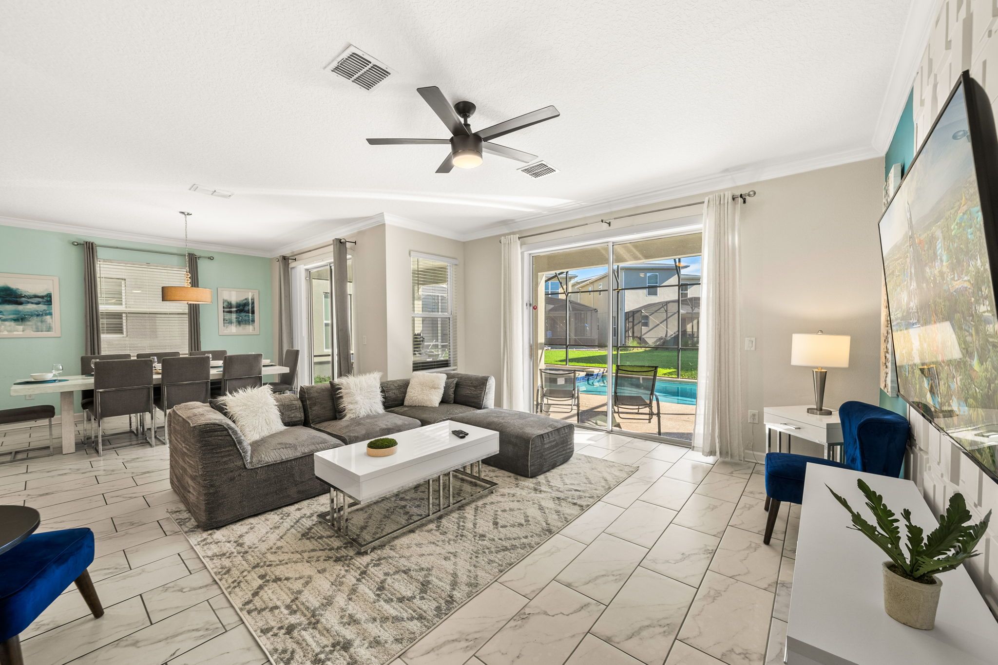 A modern living room with a sofa, coffee table, and a dining area with chairs. - 2779 Oxymoron Way (Kissimmee)