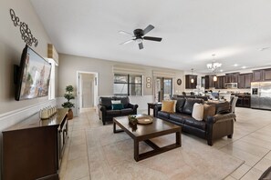 A spacious living room with a fireplace, a dining area, and a kitchen with dark cabinetry. - 1427 Wexford Way (Davenport)