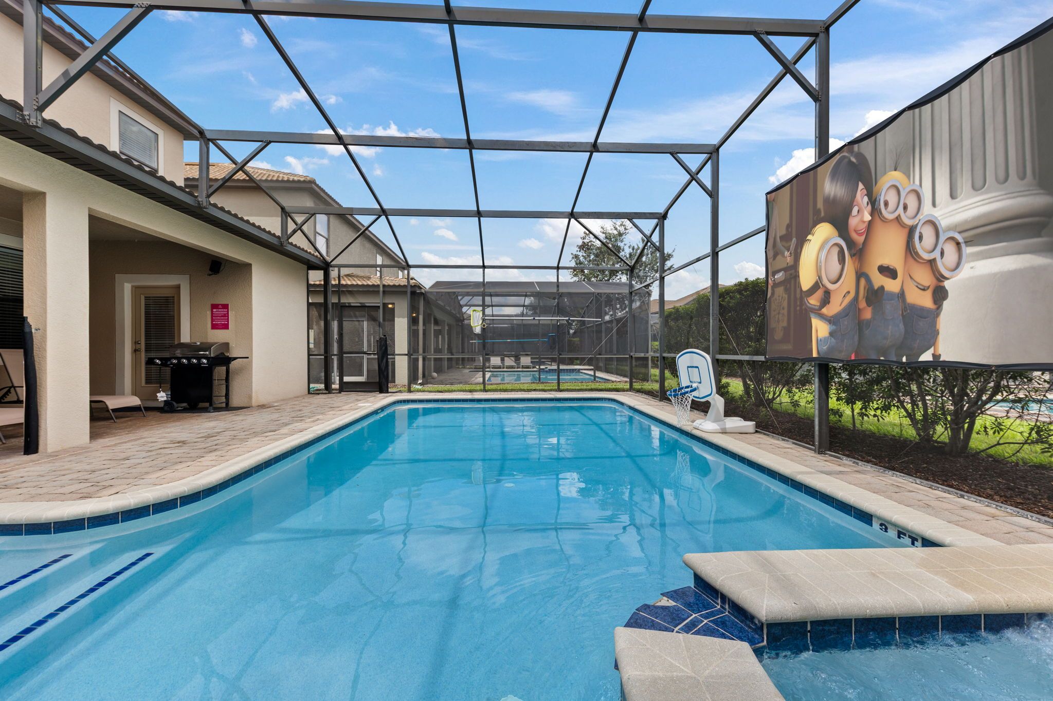 A swimming pool with a covered area, a basketball hoop, and a large cartoon character mural.