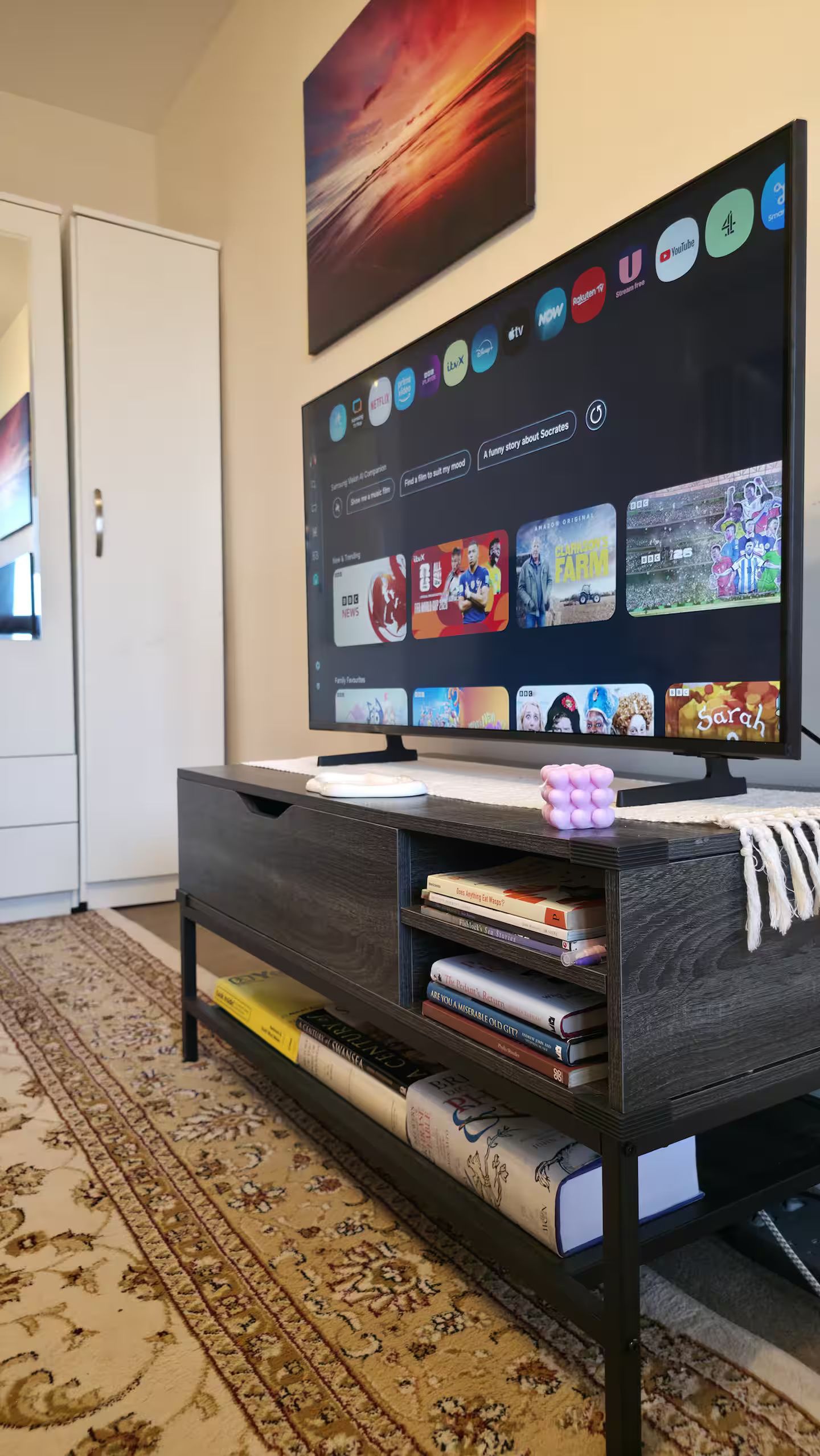 Ein Flachbildfernseher an der Wand, auf dem verschiedene Streaming-Dienste angezeigt werden.