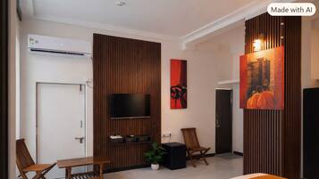 A modern hotel room with a bed, a TV, a desk, two chairs, and a plant.