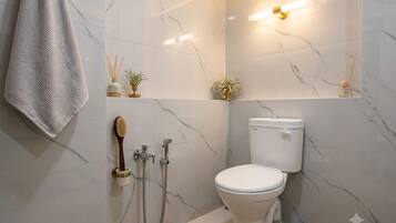 A bathroom with a toilet, shower, and towel rack.