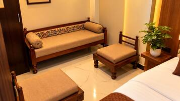 A hotel room with a bed, a sofa, a chair, and a nightstand with a plant.
