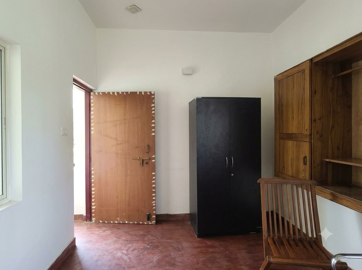 Un couloir avec une porte en bois, un meuble noir et un banc en bois.
