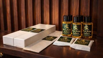A hotel room with a wooden panel wall, a white box, and four bottles of Shree Kripa shampoo.