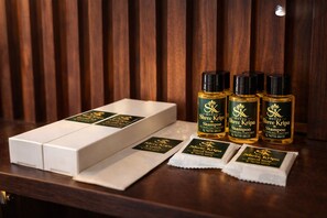 A hotel room with a wooden panel wall, a white box, and four bottles of Shree Kripa shampoo. - Hotel Shree Kripa (Ujjain)