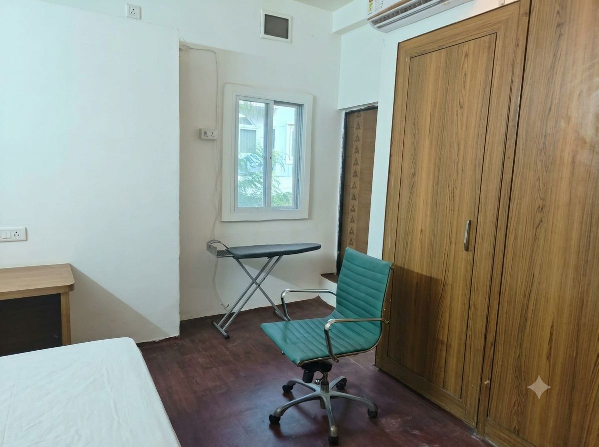 Une pièce comprenant un lit, un bureau, une chaise verte, une armoire et une fenêtre.
