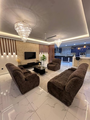 Una sala moderna con sofás cómodos, un televisor de pantalla plana e iluminación decorativa.