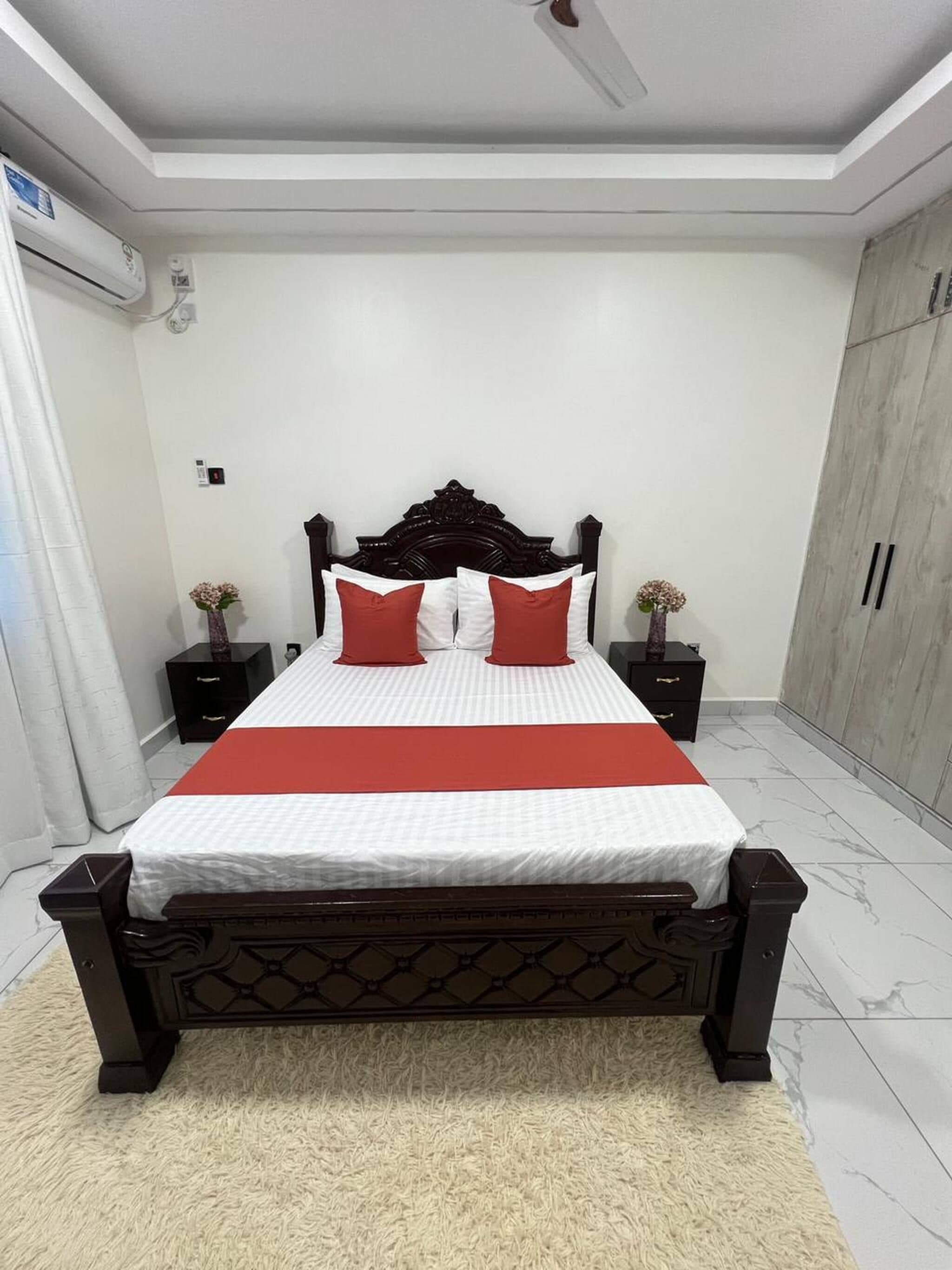 Un dormitorio con cama, mesitas de noche, un armario y un ventilador de techo.