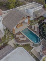Um resort com piscina, espreguiçadeiras e uma estrutura com telhado de palha.