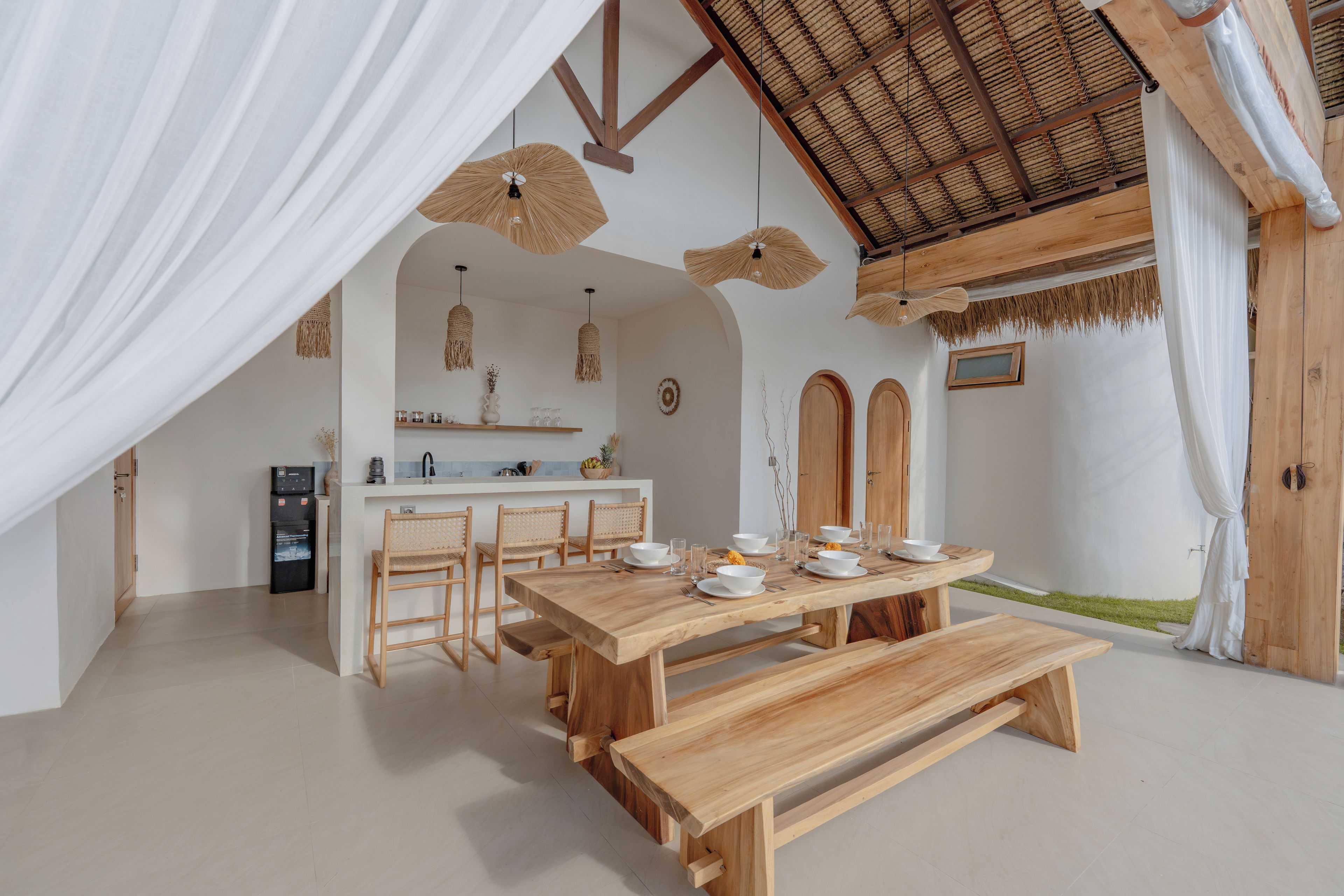 A modern kitchen with a dining area, featuring a wooden table and chairs, a built-in island, and a ceiling fan.