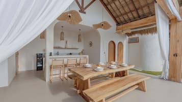 A modern kitchen with a dining area, featuring a wooden table and chairs, a built-in island, and a ceiling fan.