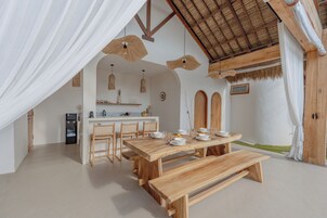 A modern kitchen with a dining area, featuring a wooden table and chairs, a built-in island, and a ceiling fan.