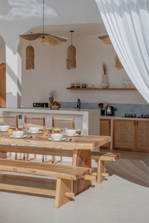Una cocina moderna con una mesa de comedor de madera para cuatro personas, una lámpara colgante y una isla de cocina con estufa integrada.