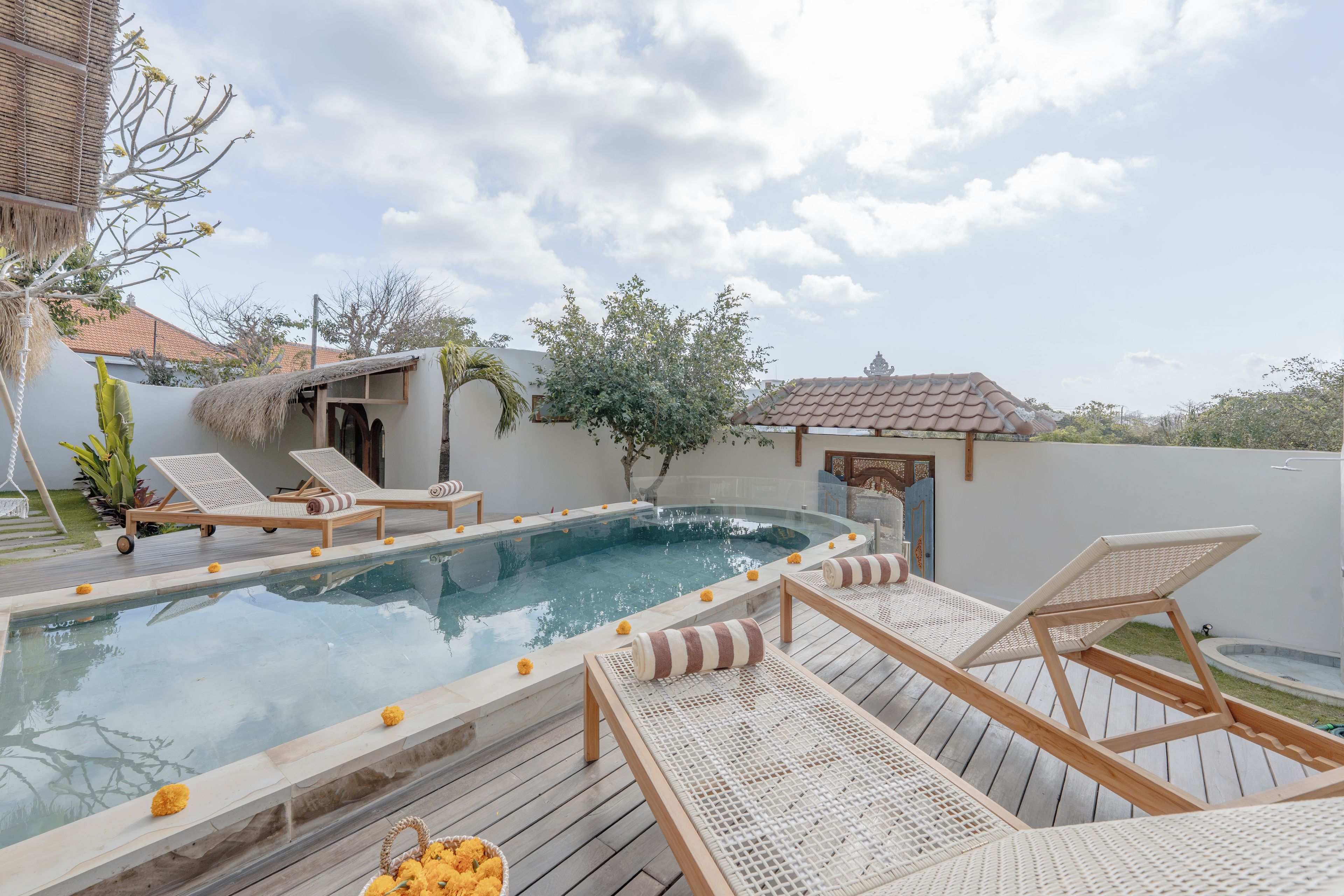 A pool area with lounge chairs and a small building.