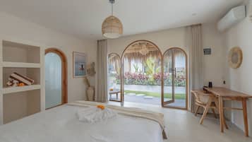 Habitación de hotel con cama, escritorio y vistas a un jardín a través de un ventanal.