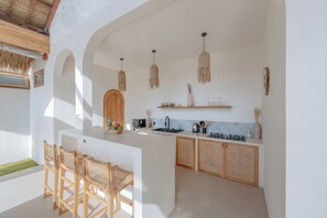 Una cocina moderna con una isla central, sillas de madera y un comedor.
