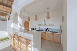 Una cocina moderna con una isla central, sillas de madera y un comedor.