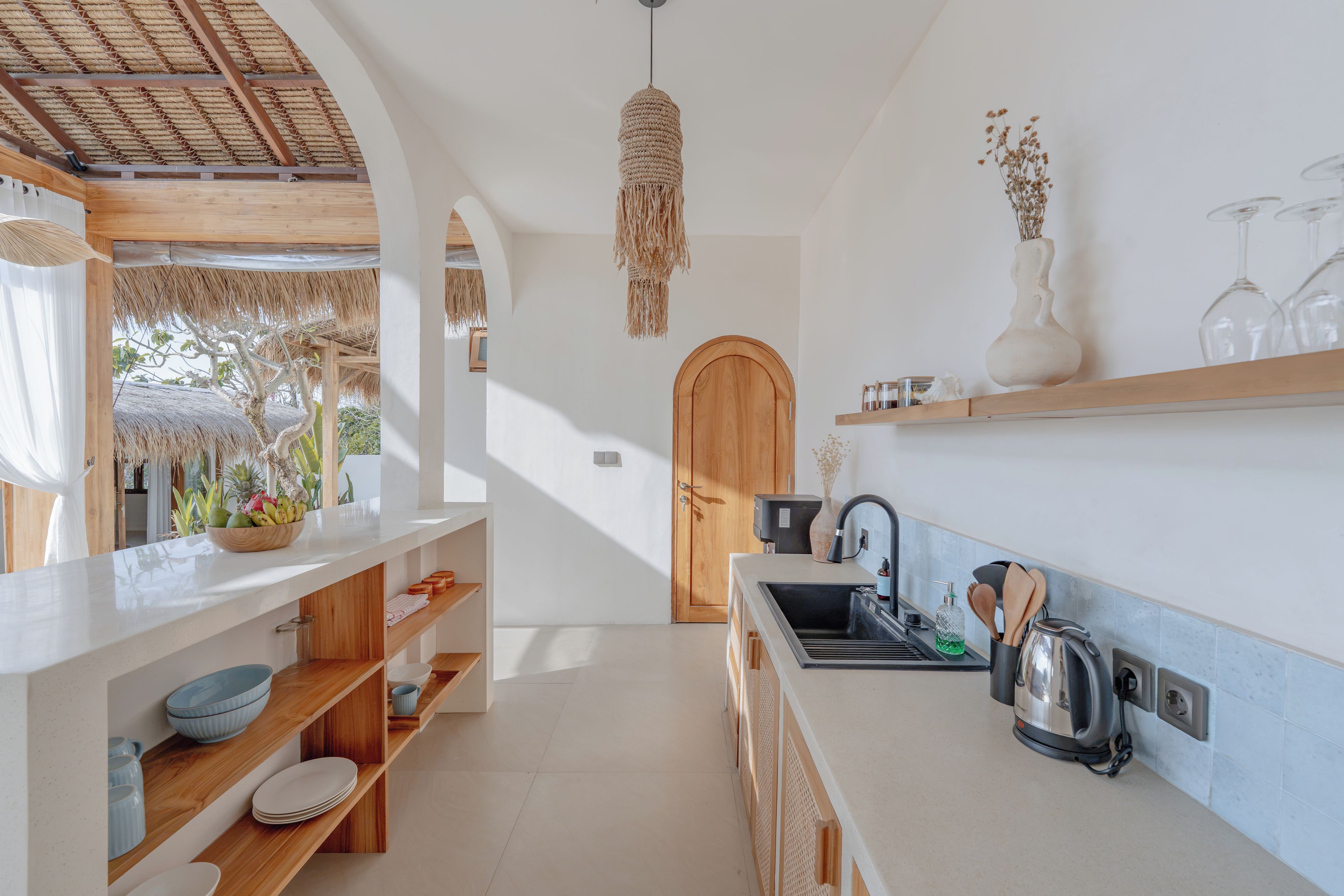A modern kitchen with a wooden countertop, a built-in sink, and a hanging light fixture.