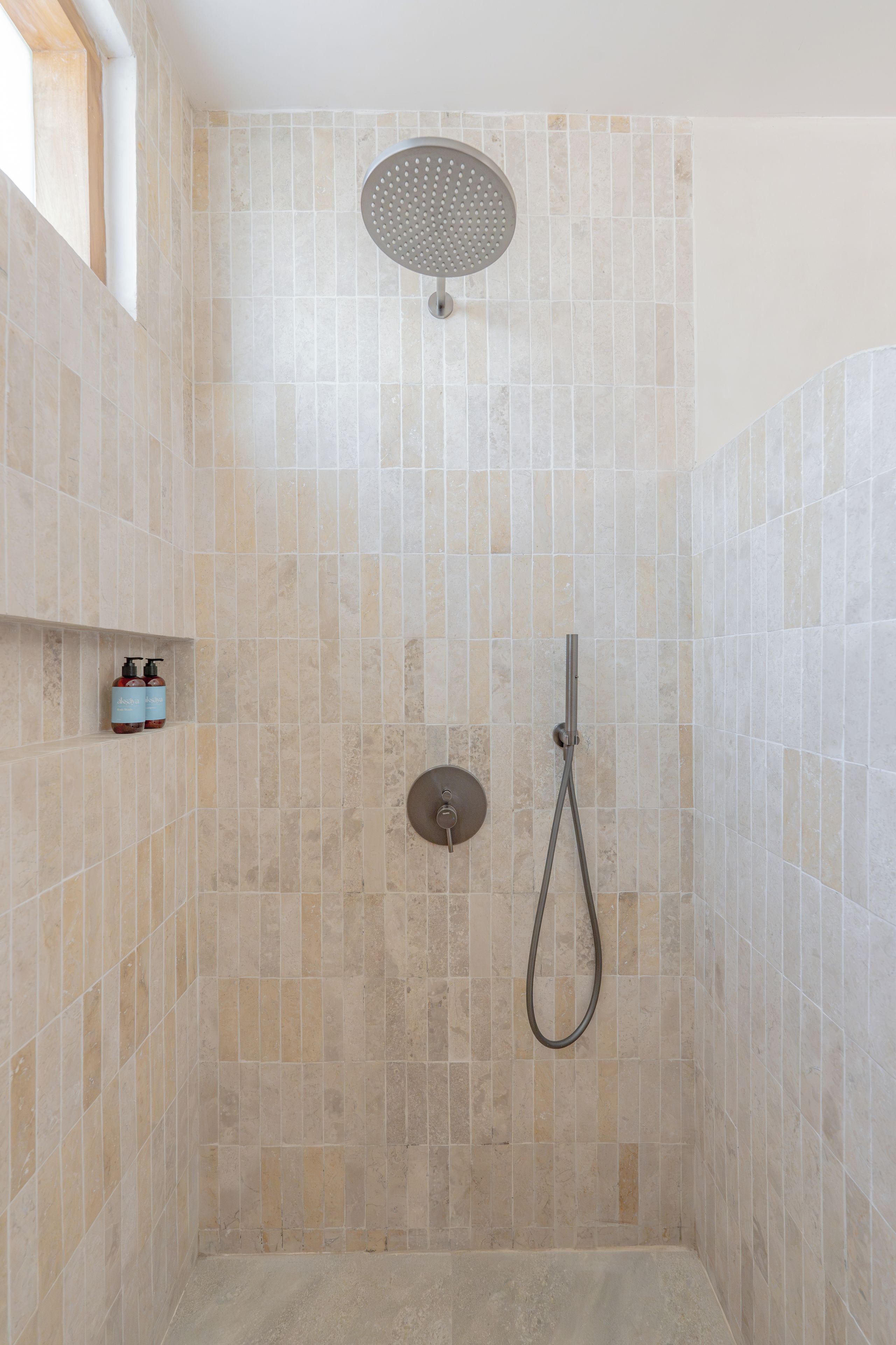 A shower with a handheld showerhead and a wall-mounted faucet.