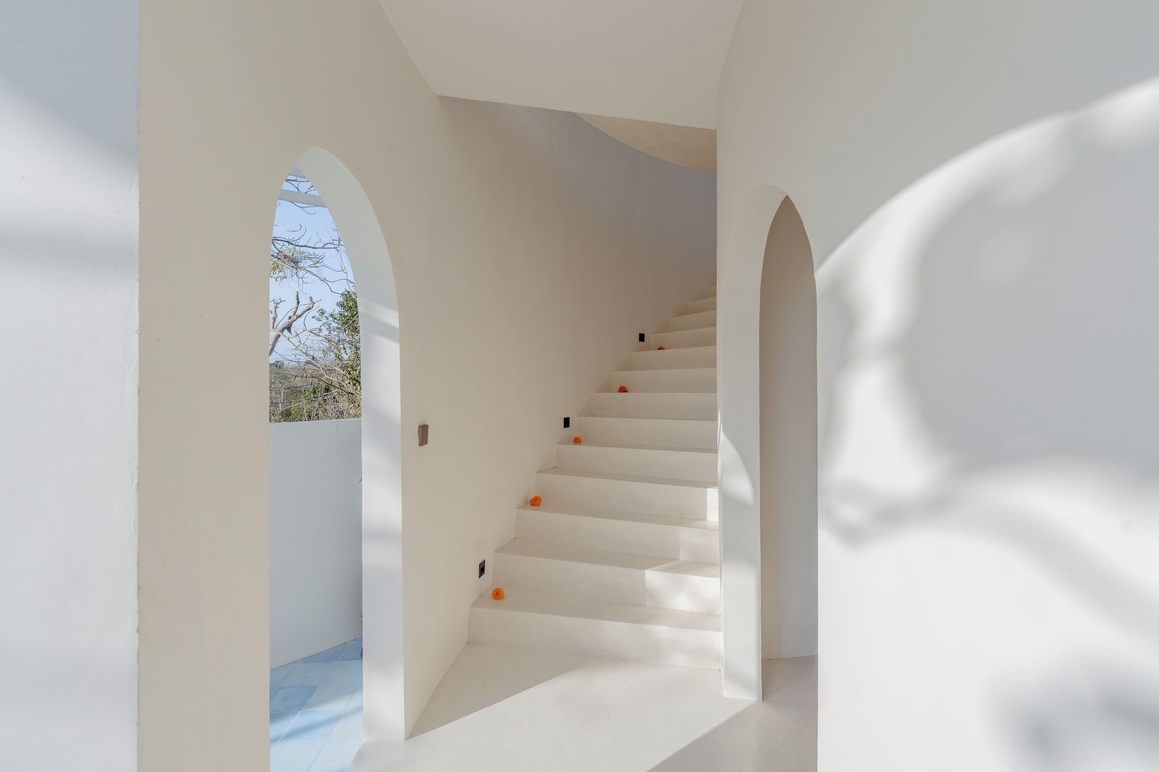 A white staircase with a view of the sky through an archway.