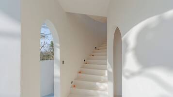 A white staircase with a view of the sky through an archway.