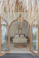 A room with a bed, a round woven rug, and a ceiling fan.