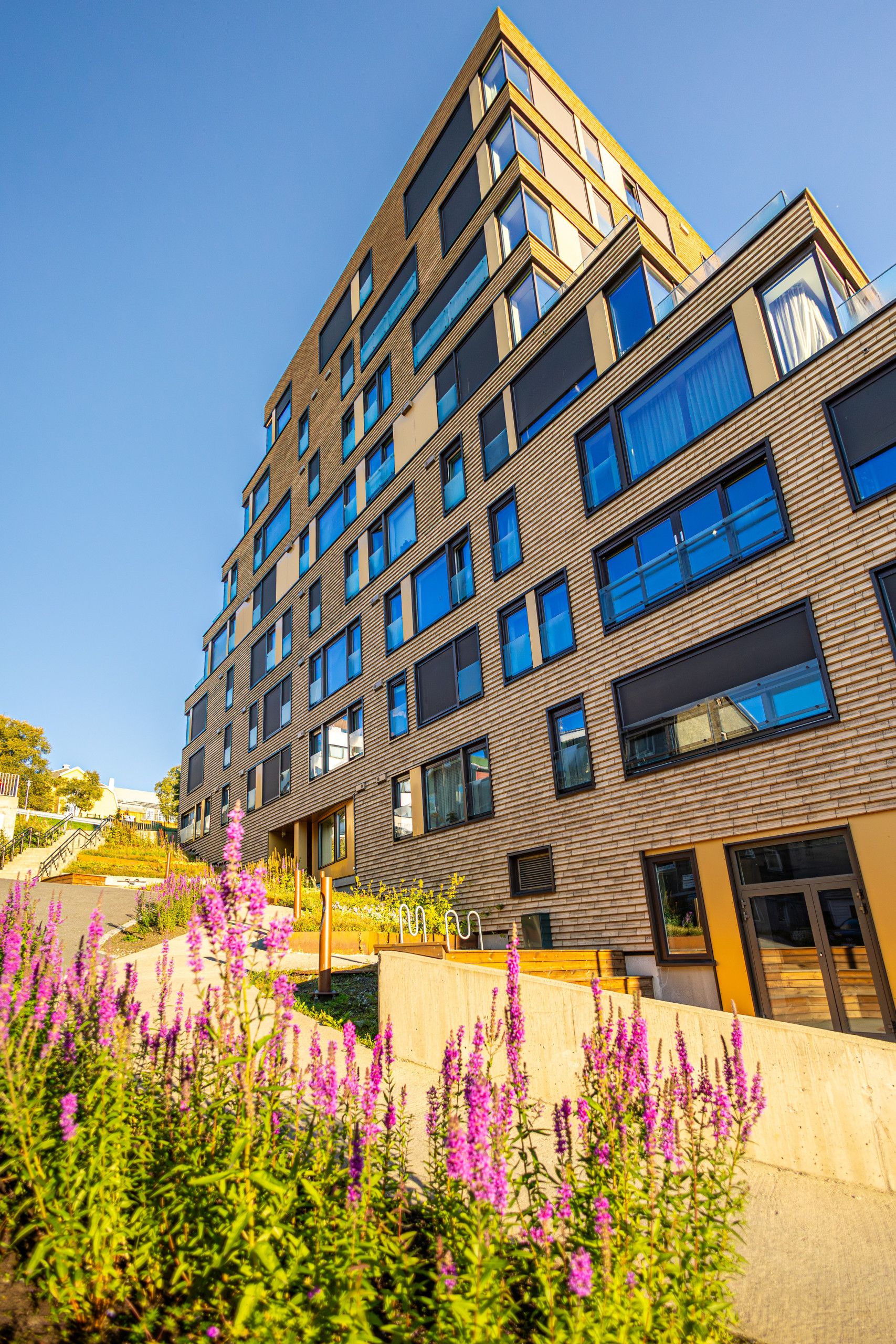 A multi-story building with a modern architectural design, featuring a mix of glass and wooden facade elements.