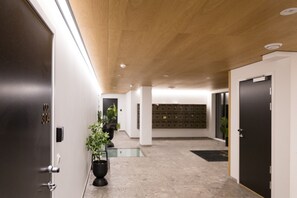 Un pasillo con techo de madera, una planta en maceta y una fila de cajas de almacenamiento.