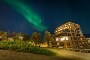A multi-story building with a modern architectural design, featuring a mix of glass and brick facades, and a well-maintained surrounding area with trees and a pathway. - Modern Apartment in Tromsø Center (Tromsø)