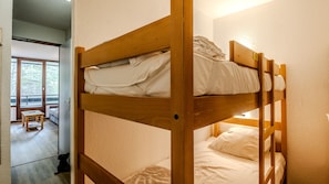 Ein Stockbett mit Holzgestell und weißer Bettwäsche.