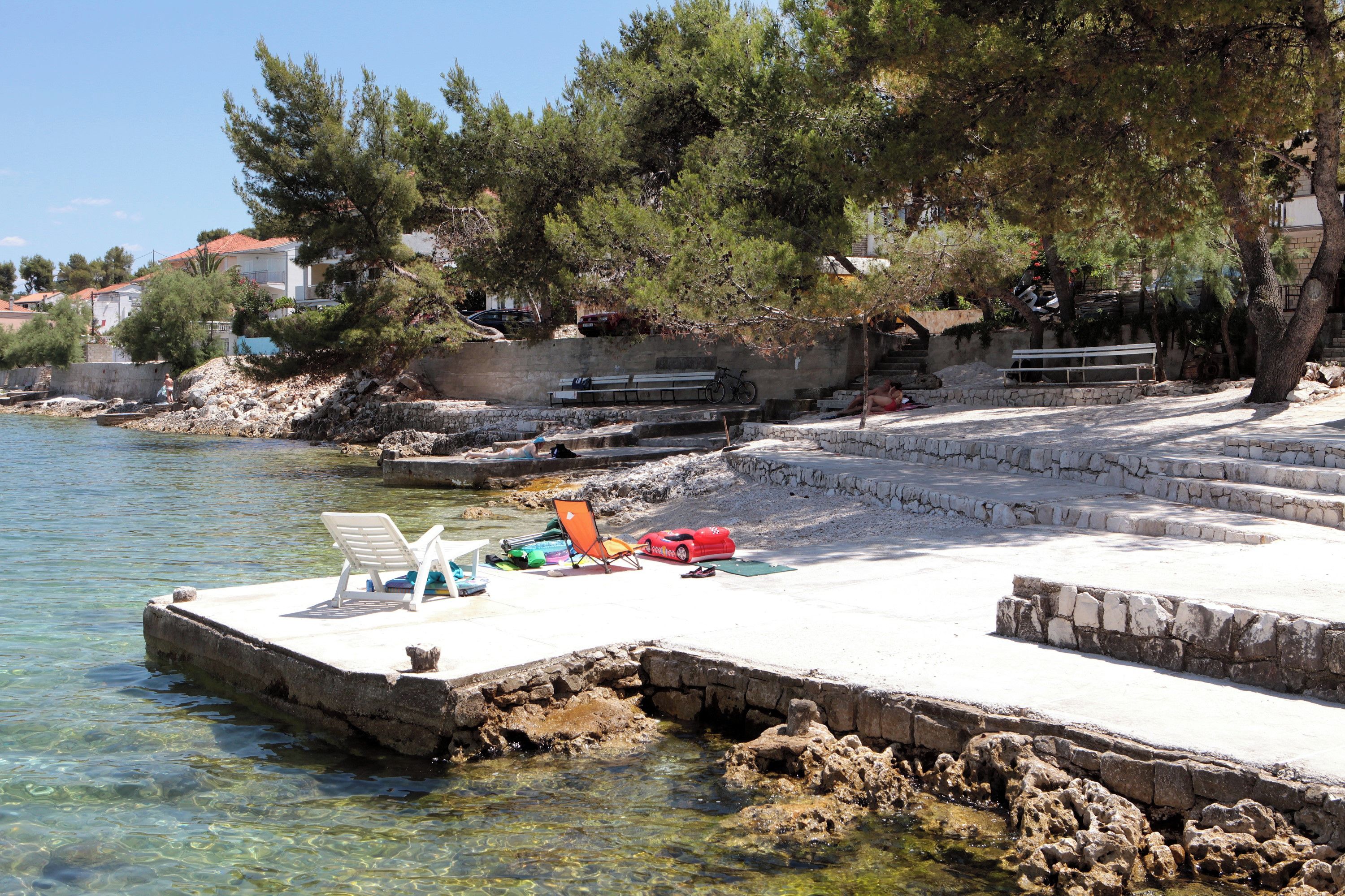 A pier with clear water, a bench, and a small boat.