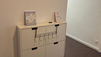 A white cabinet with two drawers and a shelf, against a plain wall.