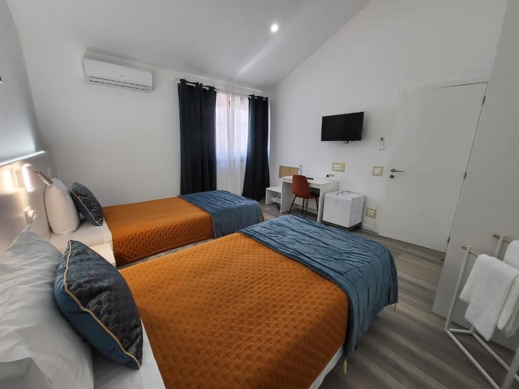 A hotel room with two beds, a desk, a chair, a TV, and a bathroom.
