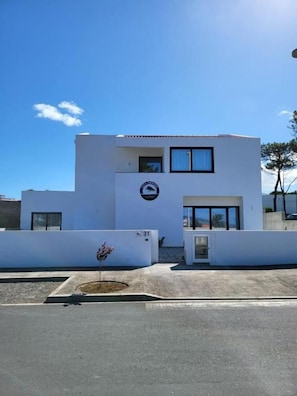 A modern building with a flat roof, a small entrance, and a sign with a logo.