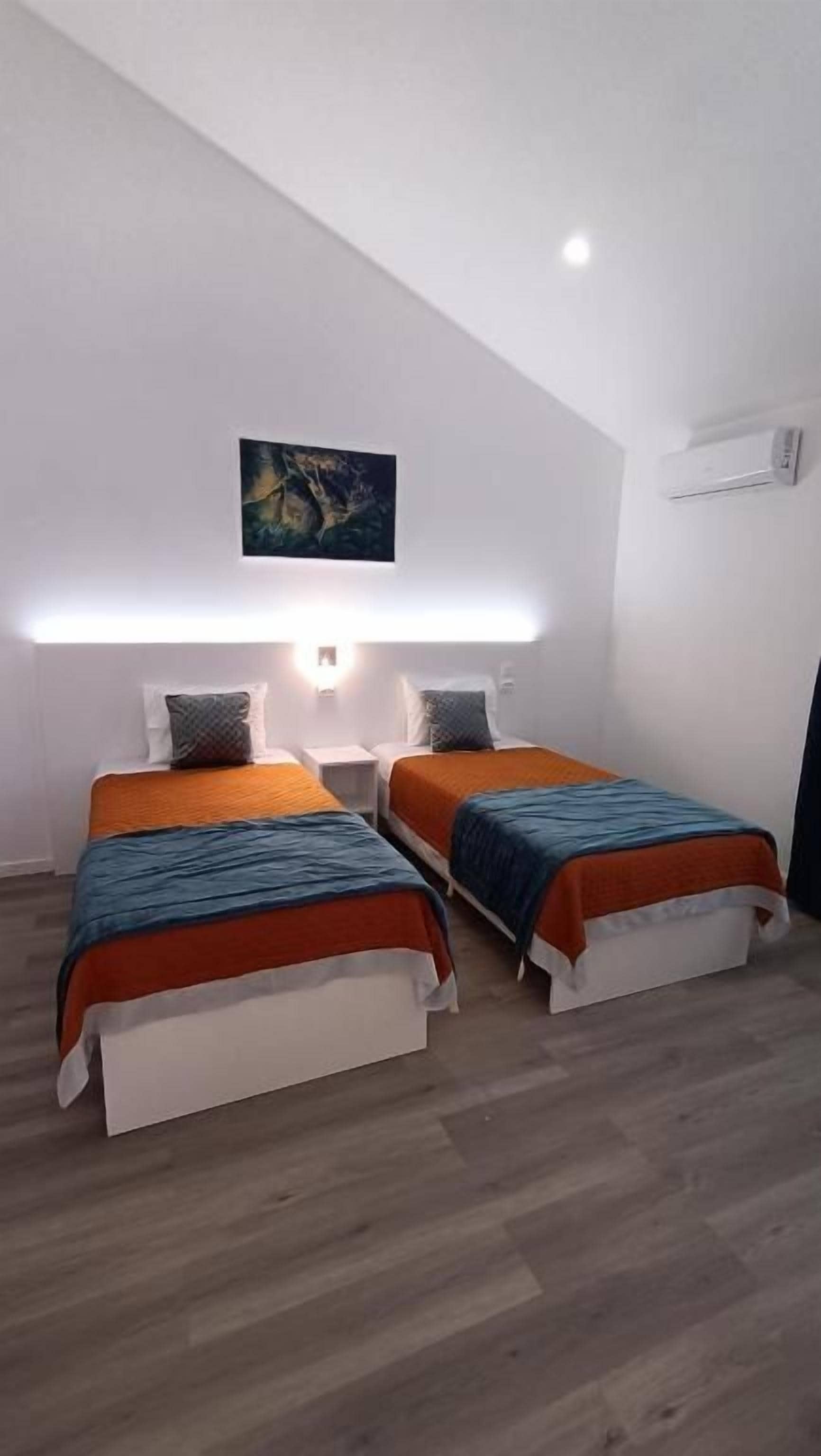 Ein Schlafzimmer mit zwei Betten, einer geneigten Decke und einem Bild an der Wand.
