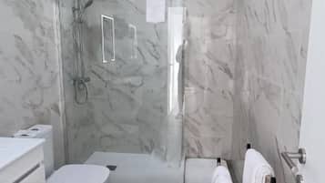 A bathroom with a shower, toilet, and sink.