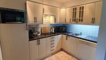 A compact kitchen with white cabinets, a microwave, a coffee maker, a toaster, and a sink.