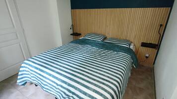 A small, neatly made bed with a striped bedspread, a wooden headboard, and two bedside lamps.