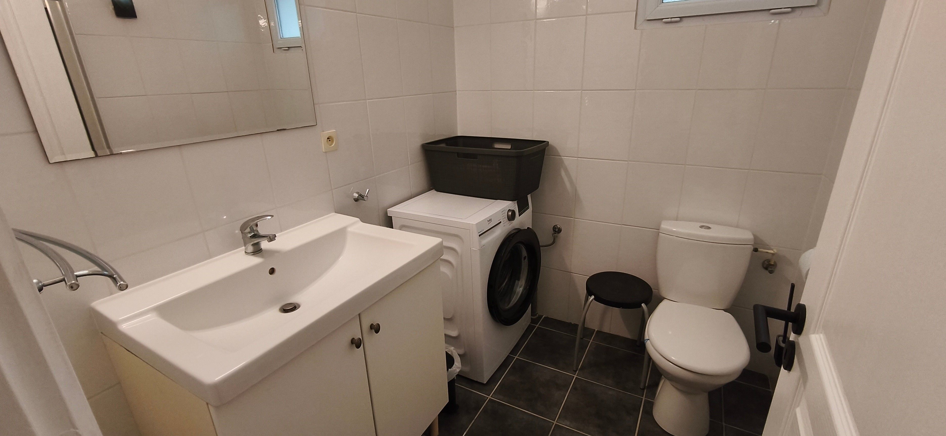Ein kleines Badezimmer mit Waschbecken, Waschmaschine, Toilette und Spiegel.