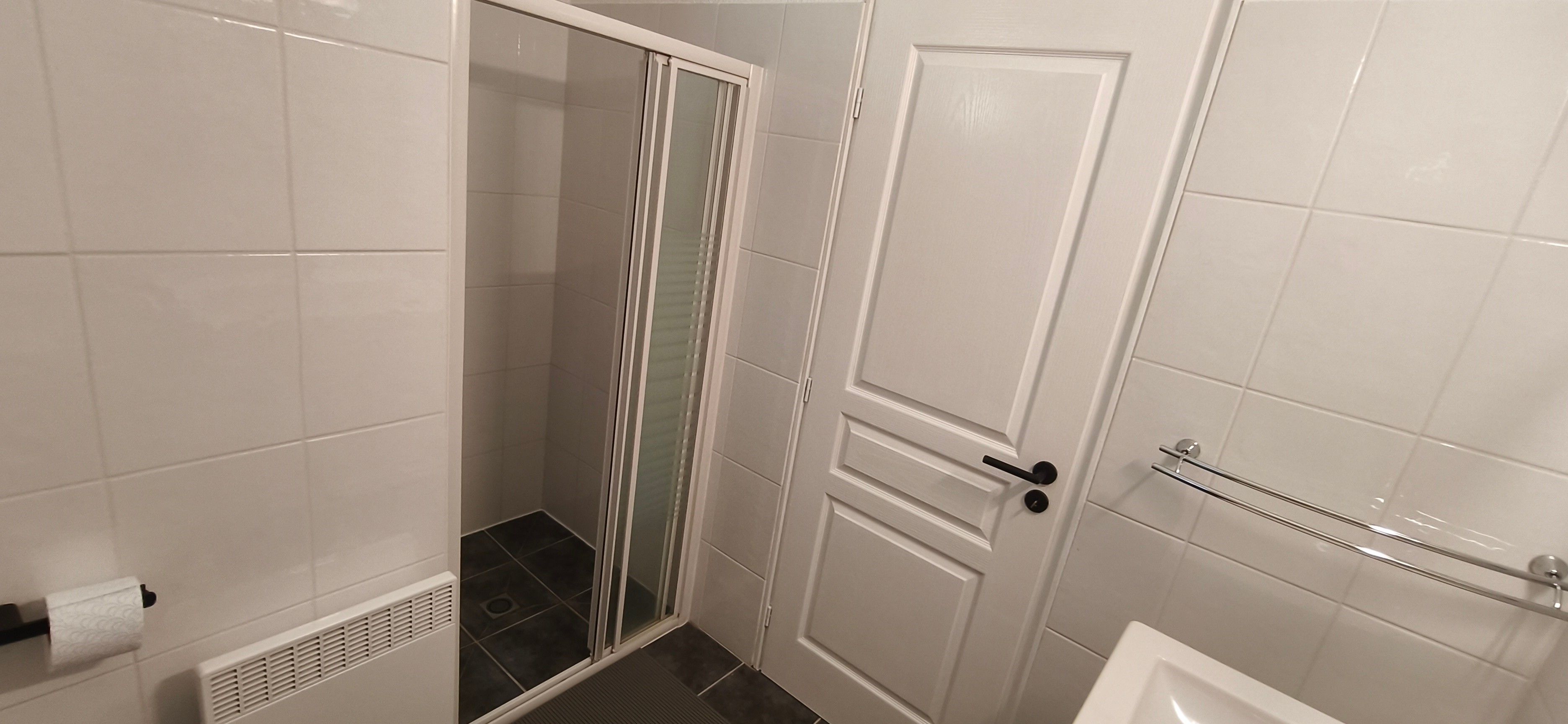 Ein Badezimmer mit Dusche, Toilette und einer Tür mit Handtuchhalter.