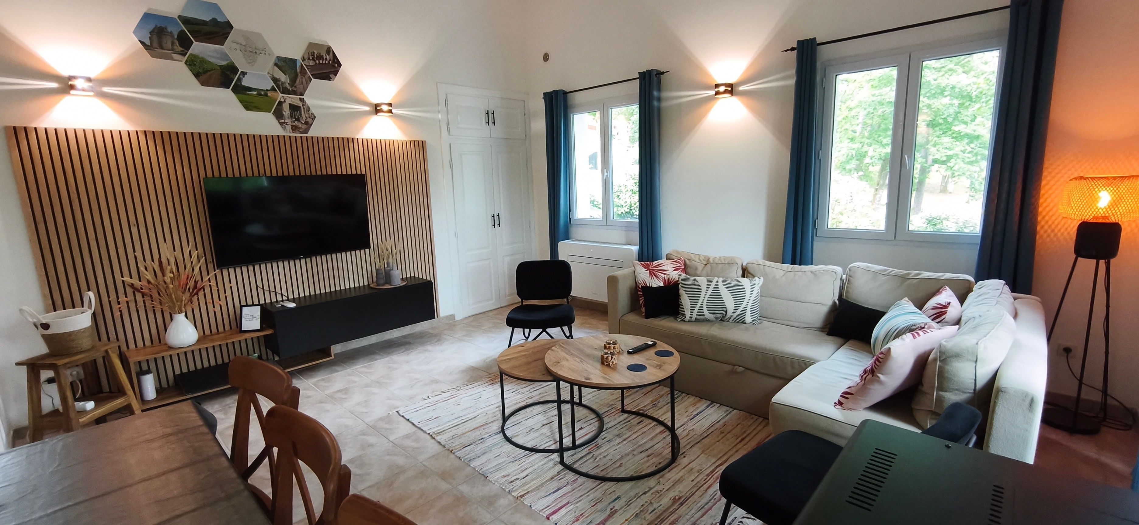 Een moderne woonkamer met een flatscreen televisie, een zithoek, een salontafel en een eethoek met stoelen.