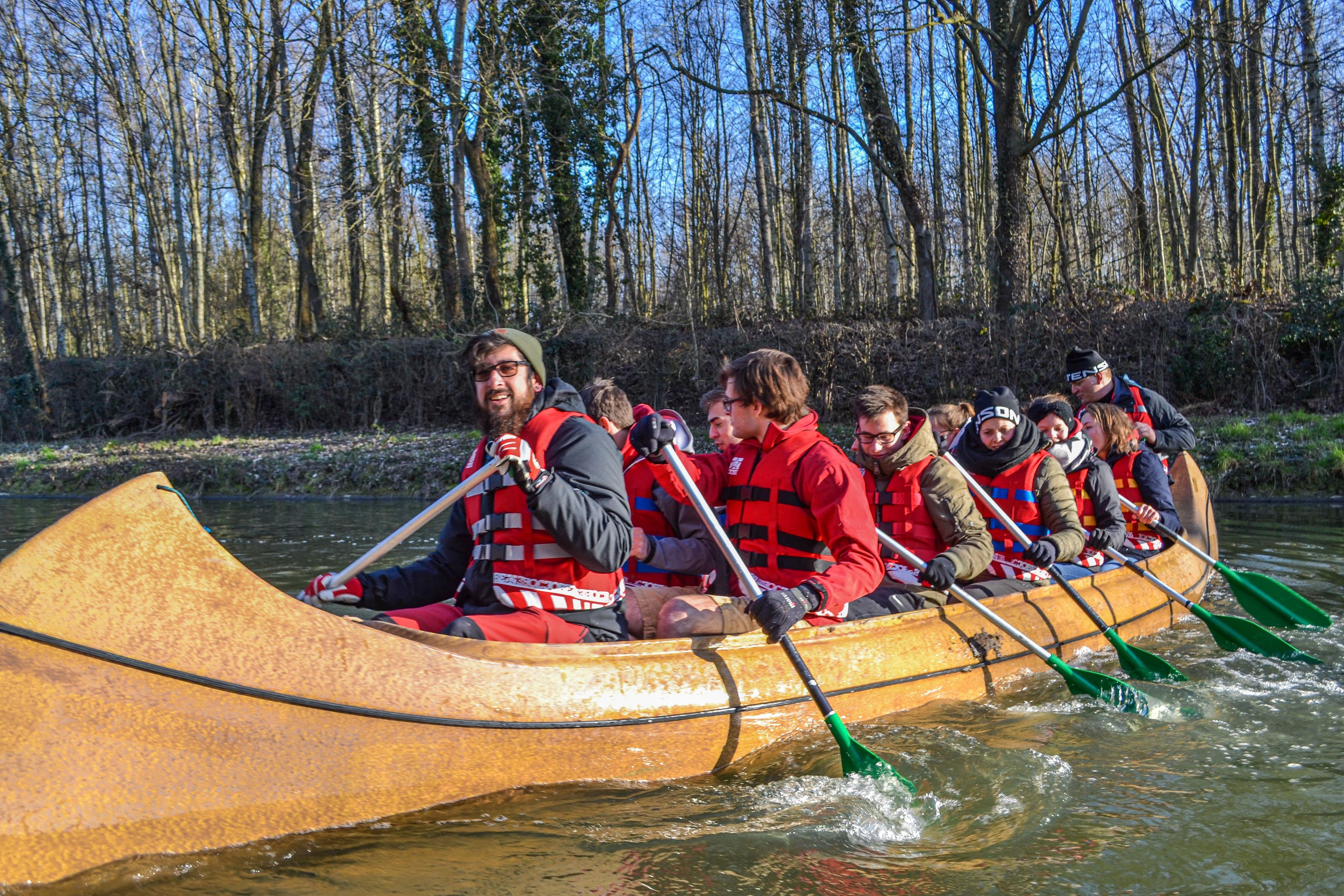 A group of people in a canoe on a river surrounded by trees.