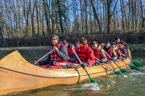 A group of people in a canoe on a river surrounded by trees.