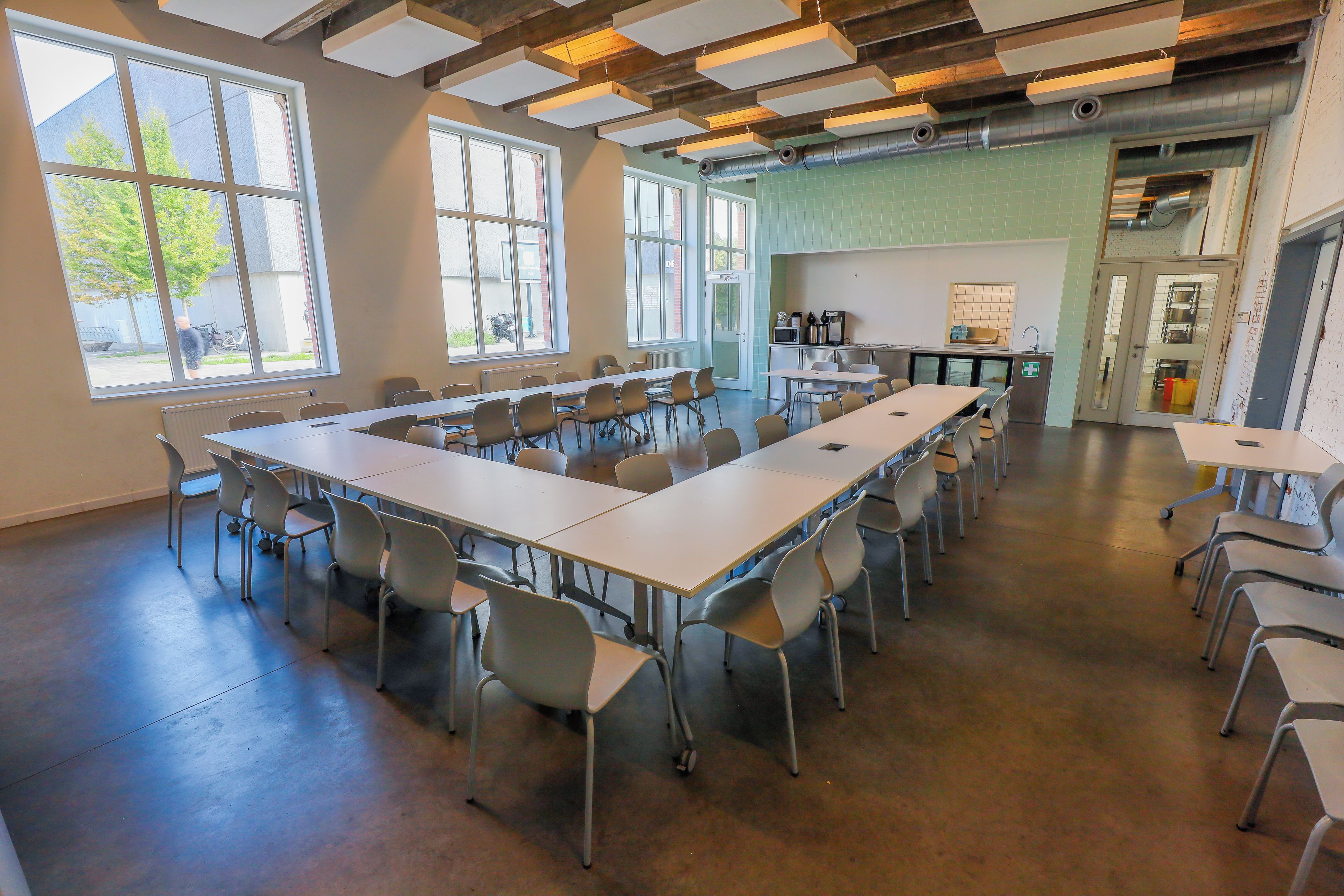 Une salle de conférence équipée d’une longue table, de chaises et d’un coin cuisine.