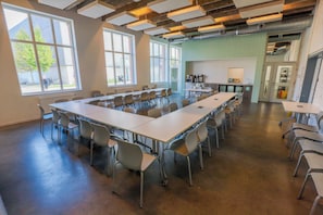 A conference room with a long table, chairs, and a kitchenette area.