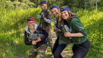 En gruppe mennesker i et udendørs miljø med træer og grøn vegetation i baggrunden.