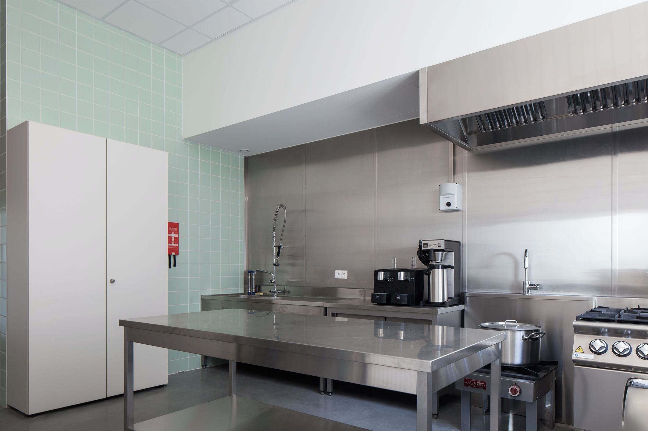 A modern kitchen with stainless steel appliances, a coffee machine, and a gas stove.