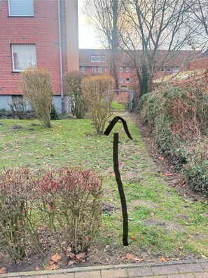 En have med forskellige buske og en metalstruktur.