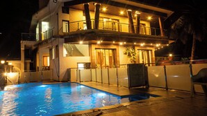 Um edifício de dois andares com piscina, escadaria e varanda.